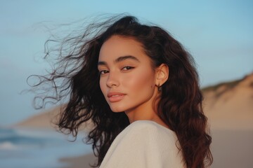 A woman with long hair is standing on a beach. She has a serious expression on her face