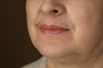Fototapeta premium Senior woman with mustache on brown background, closeup
