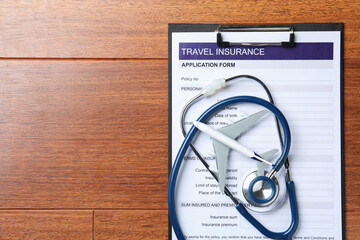 Medical tourism. Travel insurance application form, stethoscope and airplane model on wooden...