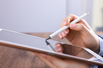 Electronic signature. Woman using stylus and tablet at wooden table indoors, closeup