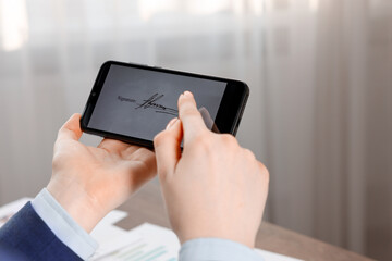 Electronic signature. Woman using smartphone indoors, closeup