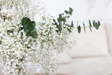 Bouquet of beautiful gypsophila flowers and eucalyptus branches indoors, closeup