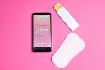 Smartphone with period calendar application and menstrual products on pink background, flat lay