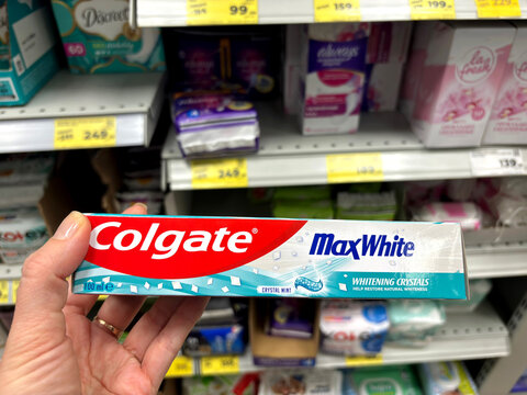 Woman's hand chooses Colgate  toothpaste in a supermarket. 