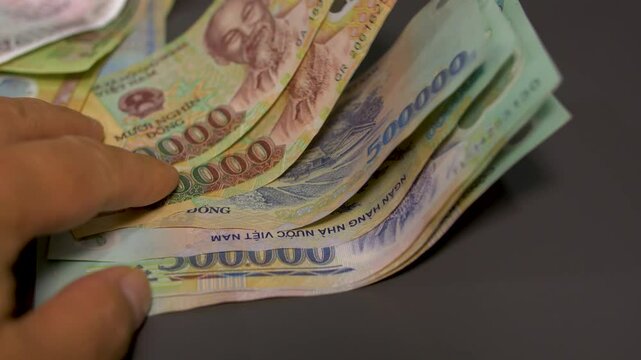 person flipping through different vietnamese dong cash bills