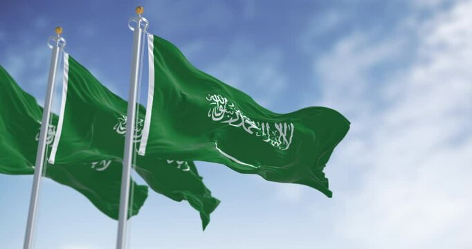 Three Saudi Arabian flags waving in the wind against a clear sky. A strong national symbol of unity, identity, and sovereignty. Seamless 3d render animation. Slow motion loop. Selective focus
