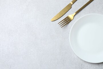 White empty plate with cutlery on a gray background