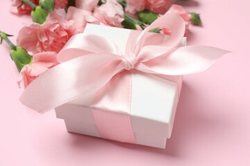Happy Mother's Day. Beautiful bouquet of pink carnations with gift box on a colored background