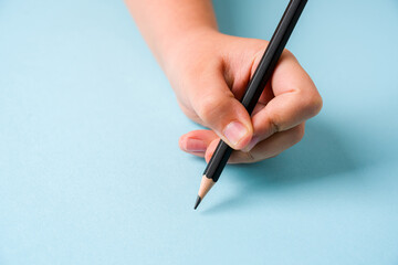 Girl holding pencil with left hand on blue background