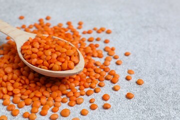 Red lentils in a spoon on a gray background