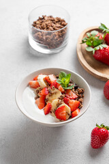 Natural Greek yogurt with homemade chocolate granola, strawberries and banana in a bowl