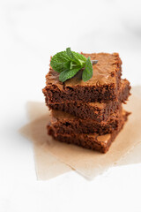 Pieces of chocolate brownies on a light background. Delicious and sweet homemade pastries for breakfast. Vegetarian dessert.
