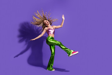 Full size photo of pretty young girl rejoice dancing wear shiny clothes isolated on violet color...
