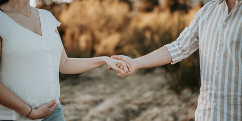 Une femme enceinte et son mari qui se tiennent par la main dans la nature