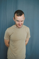 This portrait captures a joyful young man in a casual Tshirt against a gray backdrop, conveying...