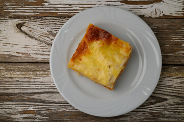 Savory slice of homemade quiche resting on a white plate against a rustic wooden backdrop during a cozy breakfast