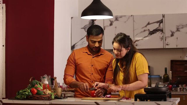 Indian couple preparing ingredients cooking meals together for family at kitchen counter