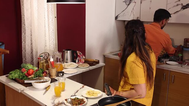 Husband and wife are eating snacks while cooking together in the kitchen