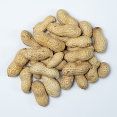Pile of unpeeled peanuts in shell close-up on white background.