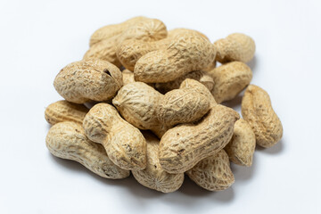 Pile of unpeeled peanuts in shell close-up on white background.