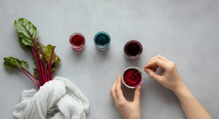 Hands preparing natural dye with beetroot, cloth, and jars on a minimalist surface