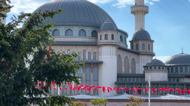 ISTANBUL, TURKEY - AUGUST 15, 2024: On a sunny day, Taksim Square offers a stunning view of the Taksim Mosque, with Turkish flags flying against the sky and the mosque's iconic minarets visible.4К