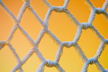 A close-up of a soccer net with intricate knots and woven threads, set against a bright yellow and orange gradient background