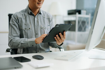 Confident business expert attractive smiling young man typing laptop and holding digital tablet on...