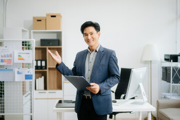 Naklejka premium Young attractive Asian man smiling thinking planning writing in notebook, tablet and laptop