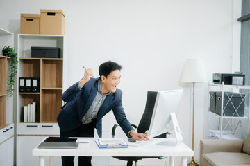 Young attractive Asian man smiling thinking planning writing in notebook, tablet and laptop