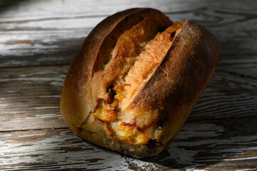 Golden crusted bread loaf rests on rustic wooden surface, inviting warmth and the aroma of fresh baking