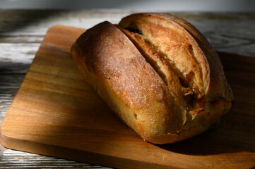 Freshly baked bread rests on a wooden cutting board under gentle afternoon light in a cozy kitchen...