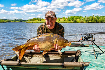Carpfishing session at the Lake.lucky fisherman holding a giant common carp.Angler with a big carp...
