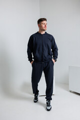 A fashionable and athletic man dressed in trendy dark sportswear represents the latest in modern...