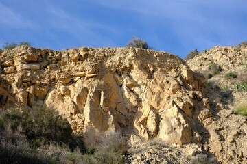 Rugged cliff face with blue sky and sparse vegetation in natural landscape