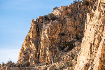 Majestic rocky cliff face with clear blue sky in sunlight