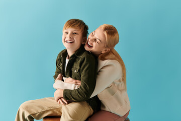 Mother and son share a joyful moment of laughter against a vibrant blue backdrop