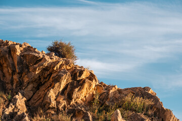 Rugged rocky landscape with bright blue sky and bush