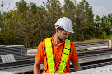 Obraz premium Male civil engineer is using tablet or smart phone conducting a quality check in a precast factory. Engineer in safety suit working in a construction factory.