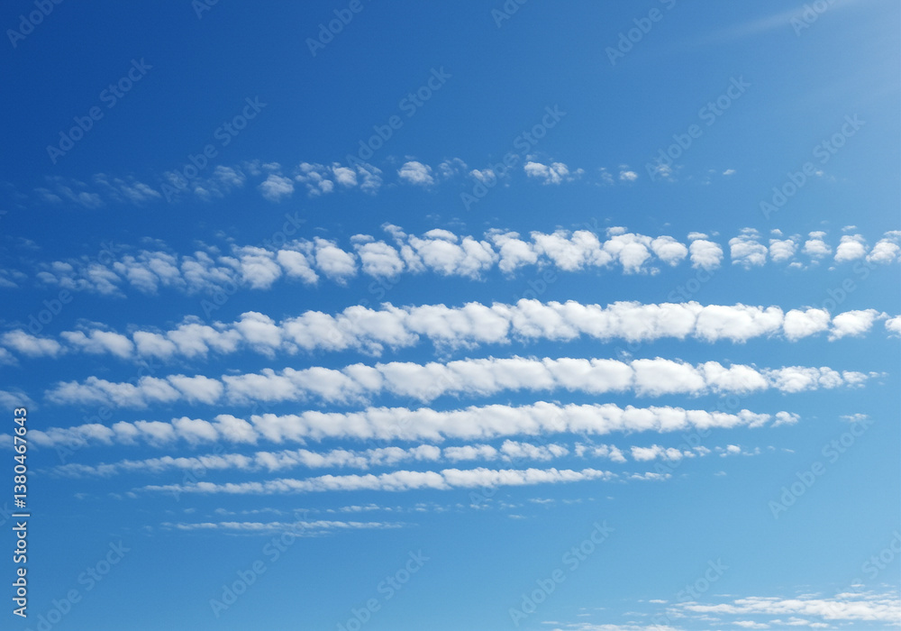 Poster clouds in the blue sky form parallel lines creating an abstract pattern of white clouds against a vi