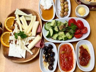 Vertical photo of a traditional Turkish breakfast with cheese, olives, honey, oil, and vegetables. A colorful spread of Turkish cuisine. Ideal for food, culture, travel, and culinary themes.