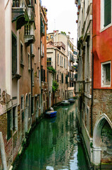 This photo, taken in March 2025, reveals a tranquil canal in Venice, with charming old buildings reflected in the calm waters and small boats moored alongside.