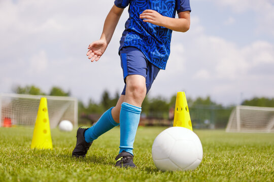 Boy attending soccer training on the school field. Young football player dribbling the ball in physical education class. Soccer practice for teenagers