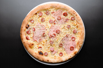 Delicious Pizza Topped with Ham and Salami on a Black Background