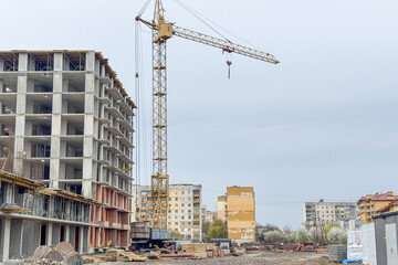 A tall construction crane stands beside a partially built concrete structure on a construction site