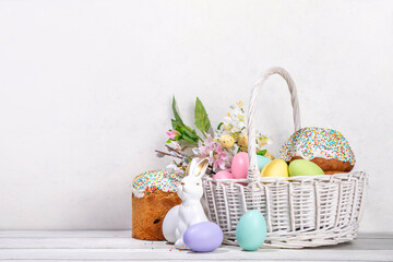 Traditional Easter basket with Easter cake, colorful pastel colored eggs, bunny rabbits decor and spring flowers. Preparation for Easter celebration, greeting card, invitation, Easter sale background