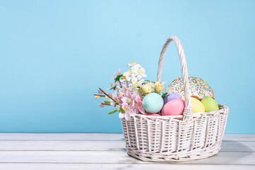 Traditional Easter basket with Easter cake, colorful pastel colored eggs, bunny rabbits decor and spring flowers. Preparation for Easter celebration, greeting card, invitation, Easter sale background