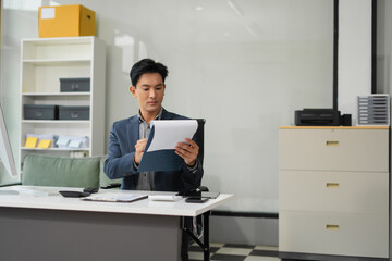 Naklejka premium Mature businessman calculate and analyzing graph document financial with report and laptop in office.