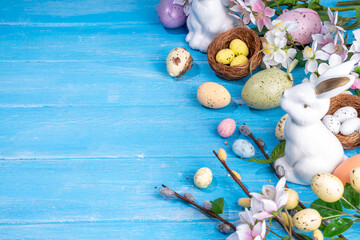 Spring Easter holiday top view flat lay background with eggs, bunny rabbits and spring flowers. Bright colorful greeting card background with copy space.