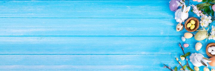 Spring Easter holiday top view flat lay background with eggs, bunny rabbits and spring flowers. Bright colorful greeting card background with copy space.